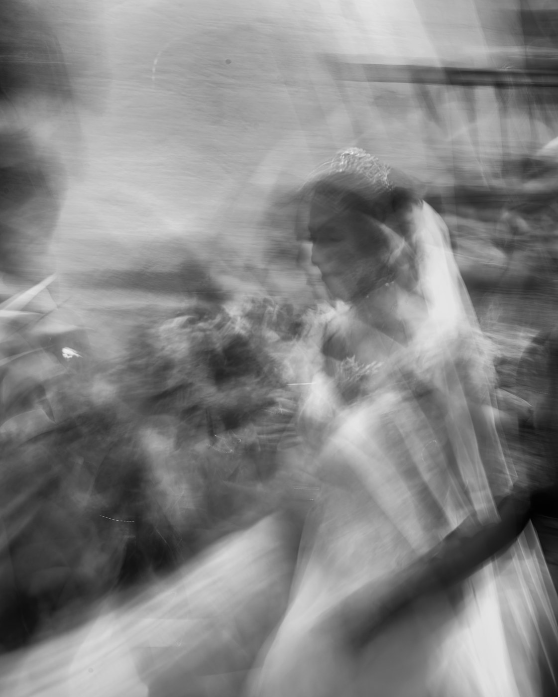 Une mariée de profil, voile et diadème, un bouquet contre elle. Tout est dissous en traînées de lumière par une pose longue ; les formes se devinent, rien n'est net.